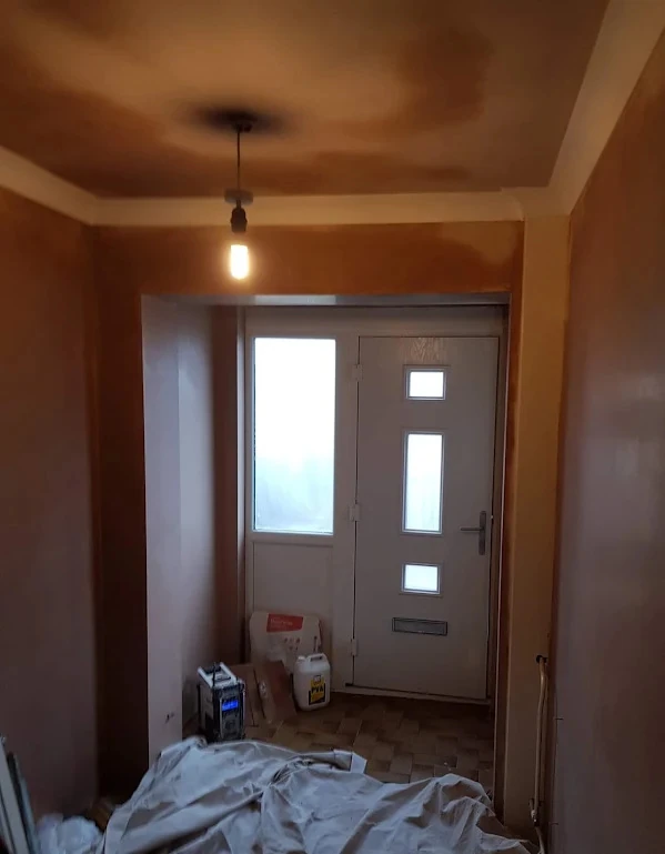 Plasterer applying smooth skim coat to a ceiling in Lowestoft